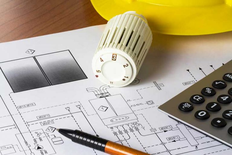 Bildausschnitt: Bauplan, Heizungsregler, Stift, Taschenrechner und Bauhelm